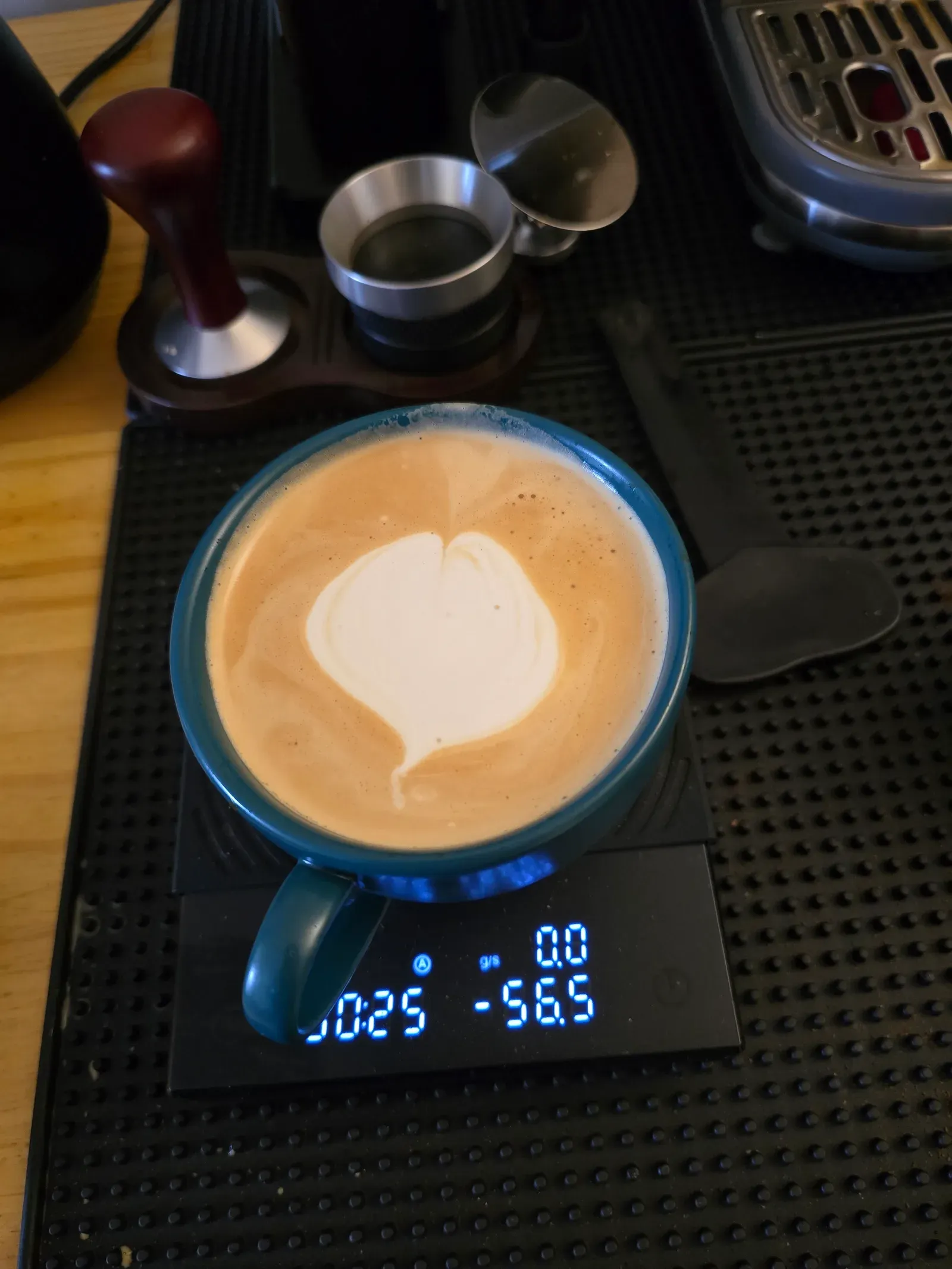 Latte in a teal cup with a heart taking shape in the milk