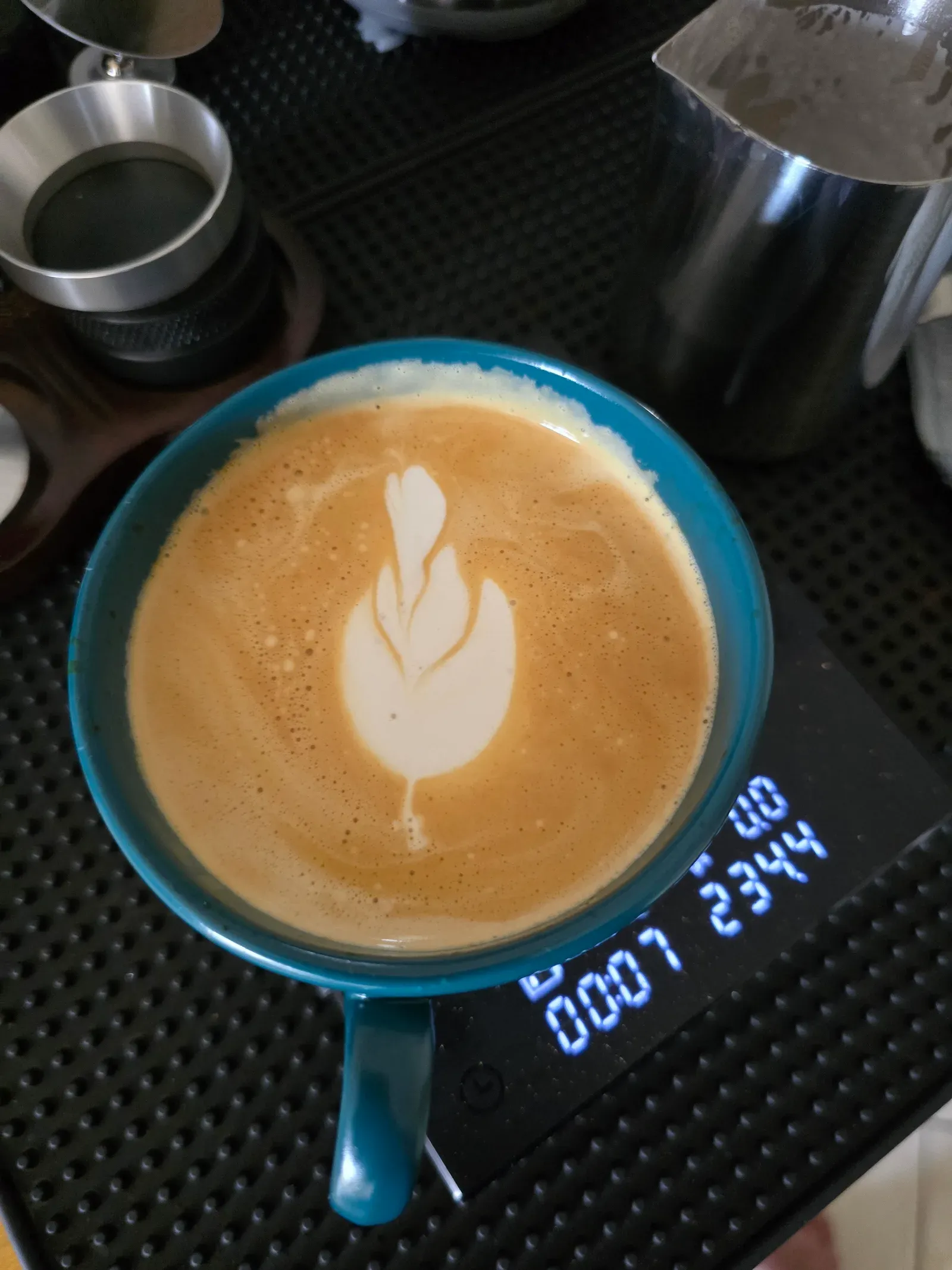 Latte in a teal cup with a small tulip: two stacked layers and a pull-through line